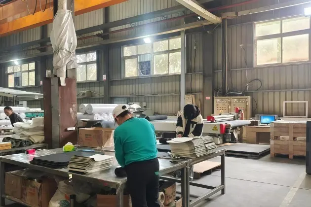 Workers handling mats in the ARTES supplier finishing workspace