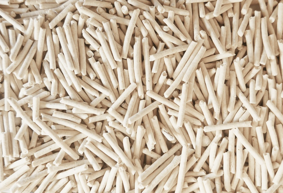 Light-coloured elongated tofu-type litter pellets in a close-up reference image